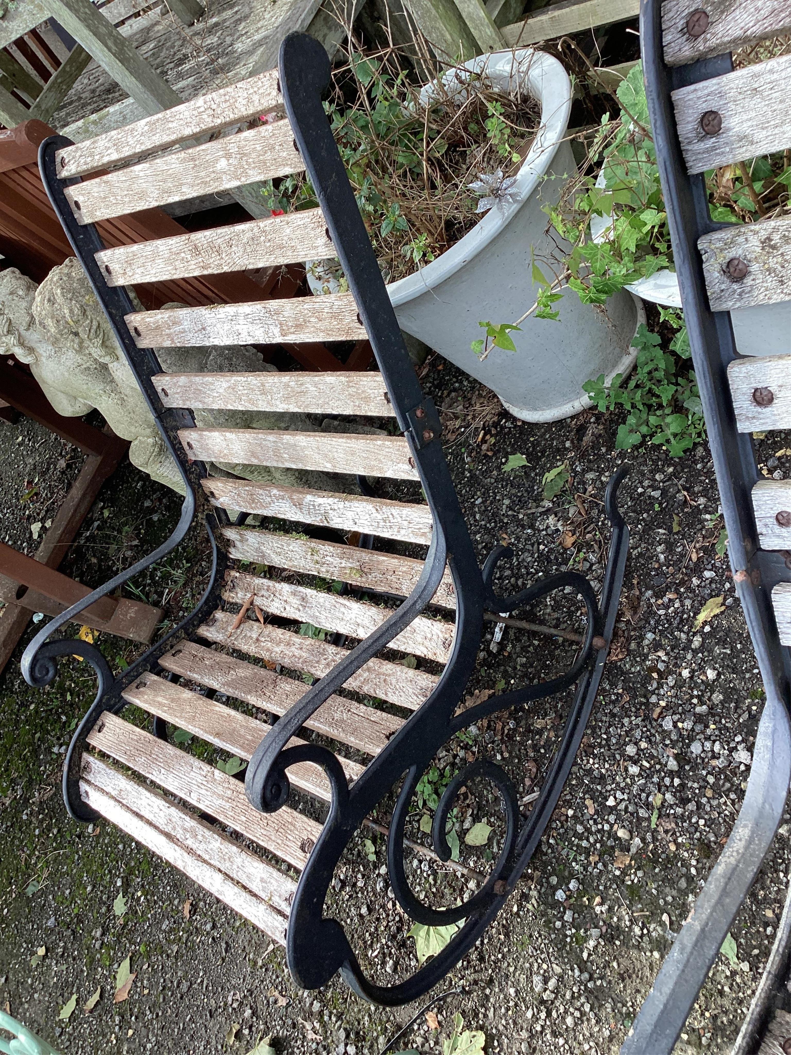 A pair of slatted cast metal garden rocking chairs